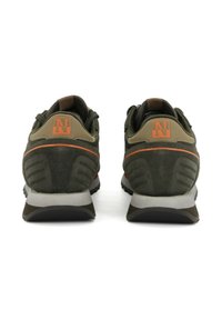 Un paio di scarpe sportive verdi e marroni viste da dietro con loghi "N" arancioni e suole bianche su sfondo bianco.