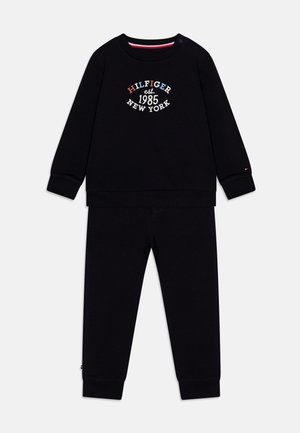 Felpa nera in cotone e pantaloni abbinati con la scritta "HILFIGER est. 1985 NEW YORK" ricamata in bianco, rosso e blu. Polsini a coste.