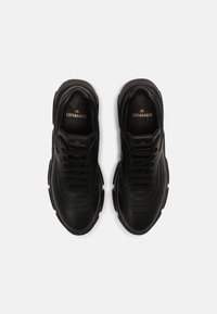 Svarta lädersneakers med ett lager-design, rund tå, tjock sula och texturerad detaljering på ovandelen. Guld-logotyp på tungan.