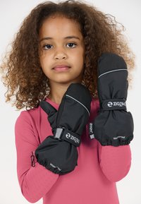 Ung pige med krøllet hår iført lyserød langærmet trøje og sorte vandtætte vanter med teksten "ZIGZAG", løftet foran en hvid baggrund.