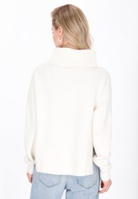 Weißer, übergroßer Pullover mit hohem Rippkragen und gerippten Bündchen. Weiche Textur, lockere Passform und hinten leicht verkürzt.