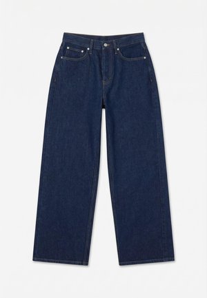 Jean en denim bleu foncé à jambes larges avec bouton frontal, fermeture éclair et conception à cinq poches, posé à plat sur fond blanc.