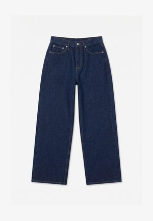 Jean en denim bleu foncé à jambes larges avec bouton frontal, fermeture éclair et conception à cinq poches, posé à plat sur fond blanc.