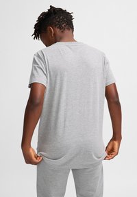 Grå kortærmet t-shirt med en afslappet pasform, lavet af blødt stof, med et enkelt design og glat tekstur, vist fra ryggen.