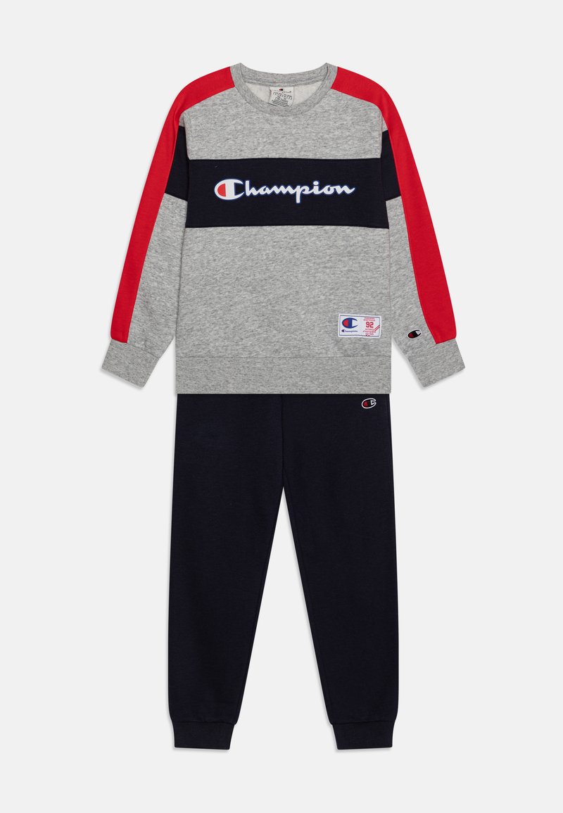Grå sweatshirt med røde og marineblå accenter, med "Champion" logo, parret med marineblå sweatpants, lavet af bomuldsstof, afslappet pasform.