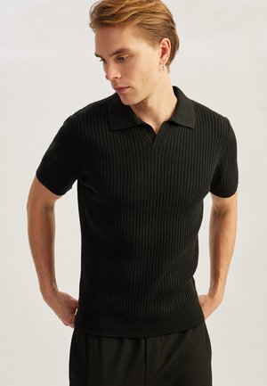Zwarte ribbelpoloshirt met korte mouwen, een klassieke kraag en een gestructureerde stof. Slim fit ontwerp met een rechte zoom.
