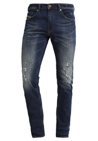 Vaqueros de mezclilla azul oscuro con corte slim, presentan desgastes en la parte delantera, un diseño clásico de cinco bolsillos y un cierre de un botón.