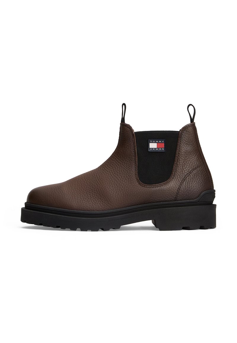 Botín Chelsea de piel marrón con paneles elásticos laterales negros, suela de goma negra, tiradores y parche del logo de Tommy Jeans en el lateral.