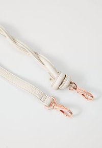 Fehér bőr öv texturált felülettel, csomózott dizájnnal és rózsaszín arany hardveres kapcsokkal, amelyek "VALENTINO" gravírozással rendelkeznek.