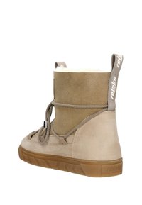 Bottine en cuir suédé beige avec une doublure intérieure douce, bout rond et semelle en caoutchouc. Présente un design lacé et un tirant en tissu à l'arrière.