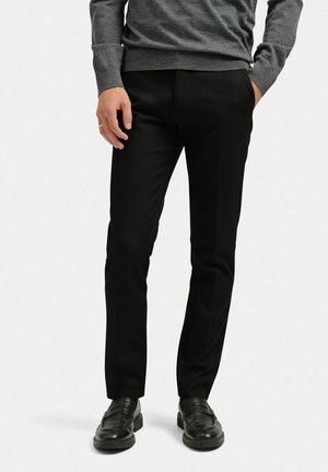 Sorte skræddersyede bukser med en glat tekstur, slank pasform, og sidelommer, parret med sorte loafers og en grå sweater.