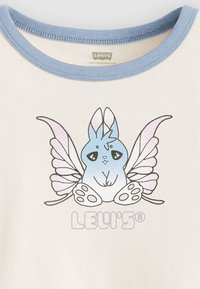 Hvit skjorte med blå krage som har en tegneseriekanin med sommerfugllignende vinger, i pastellblå og rosa farger, og "LEVI'S" trykt under.