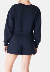 Pagliaccetto blu navy a maniche corte in tessuto morbido, con un design corto, vita elastica e polsini a costine.