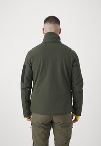 Olivově zelená waterproof bunda s vysokým límcem a černou nápletem na rameni, doplněná žlutými akcenty na rukávech. Texturovaný design látky.