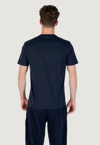 Camiseta de algodón azul marino con mangas cortas y escote redondo, vista desde atrás, con una textura suave y un ajuste relajado.