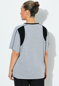 Graues kurzärmeliges T-Shirt mit schwarzen Akzenten, ausgestattet mit einem runden Halsausschnitt und lockerem Schnitt, hergestellt aus weichem, strukturiertem Stoff.