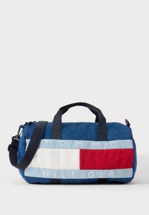 Blåt denim rejsetaske med sorte håndtag og rem, med et rødt, hvidt og lyseblåt Tommy Hilfiger logo-panel på fronten.