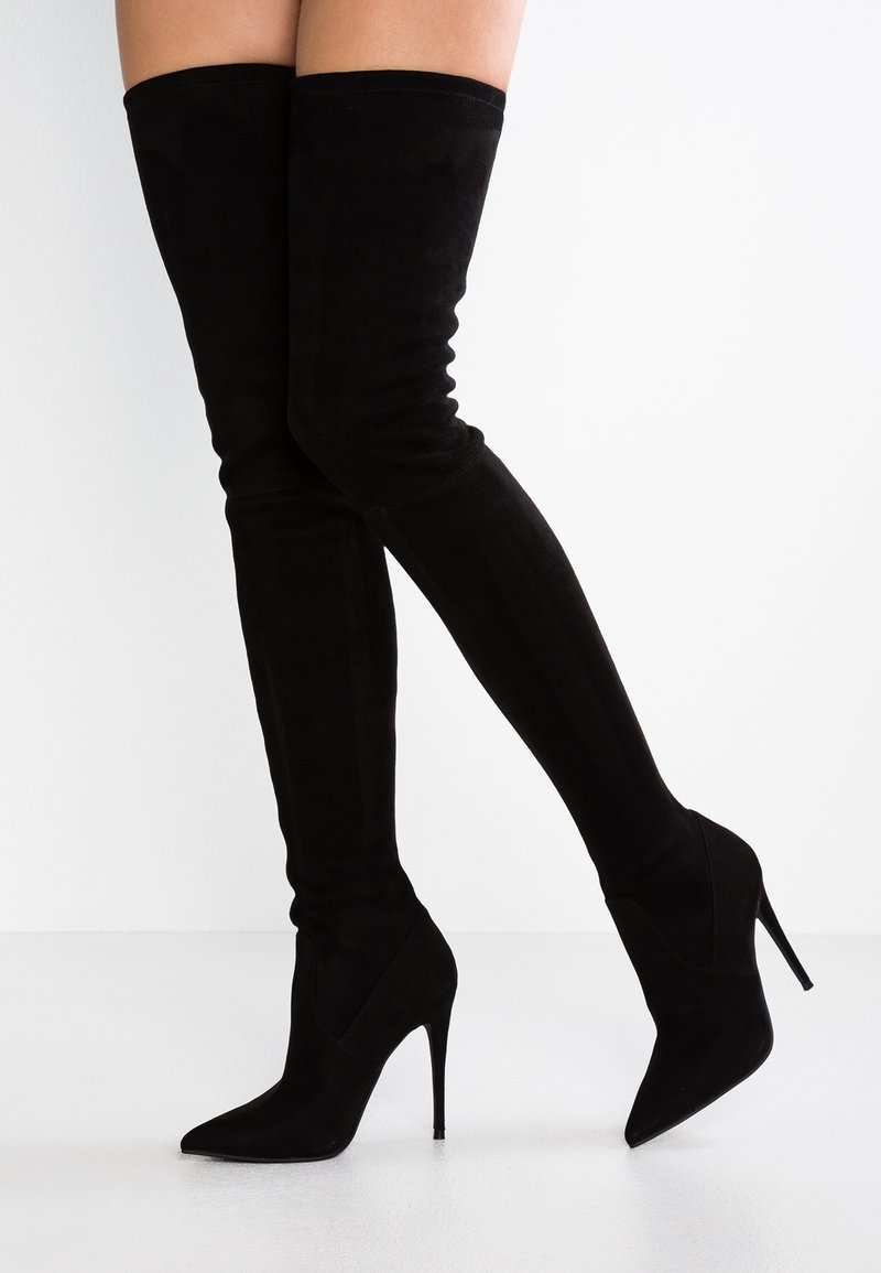 Stivali neri in suede, al ginocchio, con punta affilata e tacco a stiletto. Texture liscia, gambo aderente e costruzione senza cuciture.