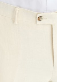 Jasnokremowe lniane spodnie o klasycznym kroju. Posiadają pojedyncze zapięcie na guzik oraz gładką fakturę.
