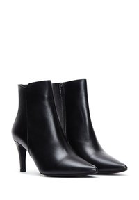 Botas de cuero negras hasta el tobillo con punta afilada, tacón alto delgado y detalles de cremallera lateral. Textura suave y diseño elegante.