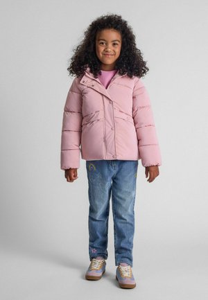 Rozā pūkainā jaka ar rāvējslēdzēju un pogu aizdari, apvienota ar gaiši ziliem džinsiem, kuros ir varavīksnes un zvaigznes izšuvumi, kā arī pasteļkrāsas kedām.