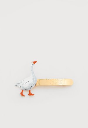 Barrette à cheveux Moschino dorée avec une figure d'oie en émail blanc et orange fixée à une extrémité.