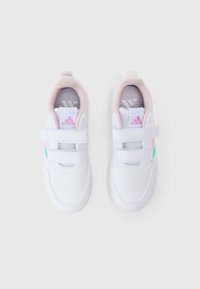 Zapatillas deportivas blancas con una parte superior sintética lisa, acentos en colores pastel, correas de velcro y un cuello acolchado para mayor comodidad.