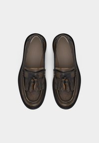 Φθαρμένα σκούρα καφέ δερμάτινα μοκασίνια με λεπτομέρειες φράντζας και φουντίτσας, ορατά από πάνω σε λευκό φόντο.