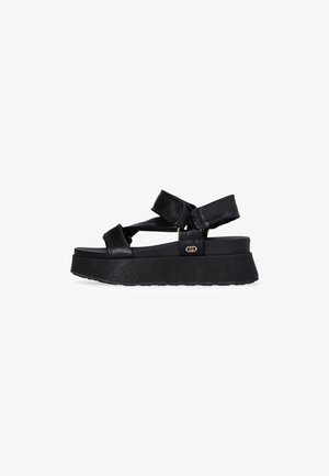 Sandali platform neri con cinturini testurizzati, fibbia regolabile e suola spessa. Progettati con un'estetica minimalista e moderna.