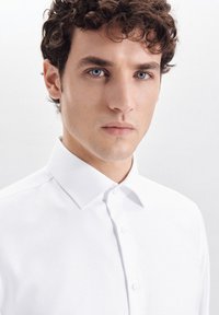 Witte blouse met een textuurstof, met een knoopsluiting en een schone, minimalistische uitstraling. Effen oppervlak zonder patronen.