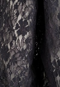 Čierna čipkovaná tkanina s kvetinovými vzormi, zložitými detailmi a jemným, textúrovaným povrchom s delikátnym, polopriehľadným vzhľadom.