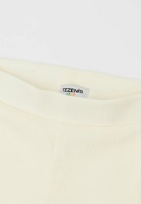 Krémový žebrovaný pás dětského oblečení s etiketou s nápisem "TEZENIS KIDS." Tkanina vypadá jemně a pružně.