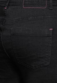 Jeans in denim neri con una tasca posteriore con cuciture rosa, una forma di tasca classica e una finitura liscia, leggermente testurizzata.