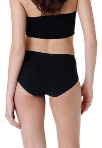 Slip neri a vita alta realizzati in tessuto morbido, caratterizzati da una texture liscia, cuciture sottili e un design pulito e minimalista.