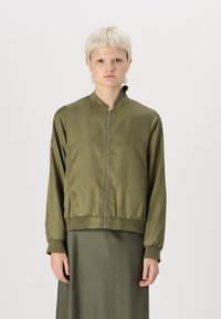 Giacca bomber verde oliva realizzata in tessuto liscio, con zip frontale, colletto rialzato e polsini e orlo a coste.