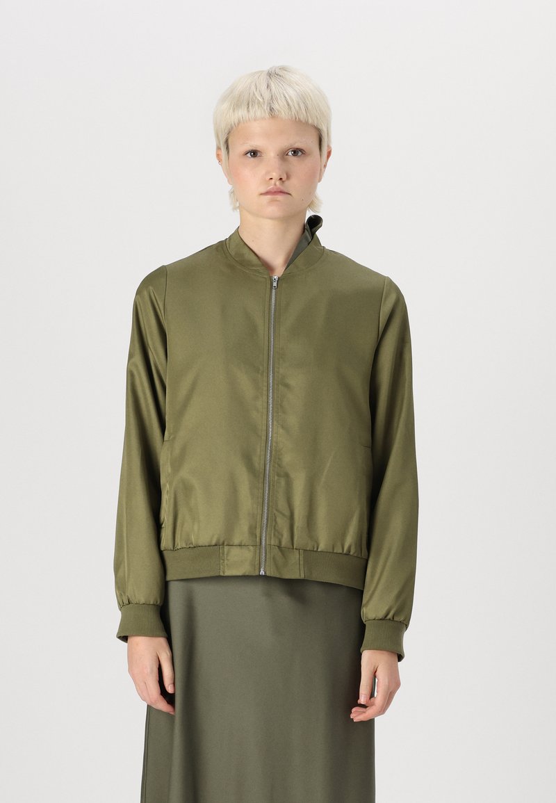 Giacca bomber verde oliva realizzata in tessuto liscio, con zip frontale, colletto rialzato e polsini e orlo a coste.