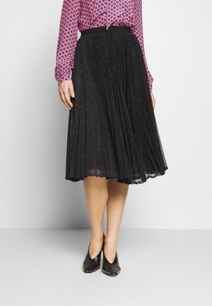 Jupe midi plissée noire avec une texture pailletée, dotée d'une taille lisse. Associée à un blouse rose à motifs et des chaussures noires à bouts pointus.