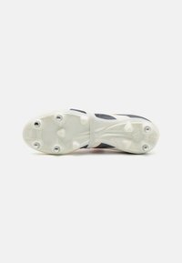 Football cleat with a white sole, black upper, and red accents. Features a textured design and six prominent studs for traction.