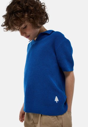 Polo shirt bleu en maille à manches courtes avec un col et un ourlet côtelés, ornée d'un logo d'arbre blanc en bas à gauche.