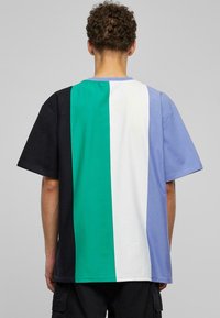 Krāsu bloku T-krekls ar melniem, zaļiem, baltiem un gaiši ziliem segmentiem. Izgatavots no mīkstas auduma, ar brīvu piegriezumu un īsām piedurknēm.