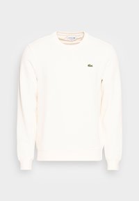 Bílá mikina z bavlny s výstřihem do V. Má žebrované manžety a malý zelený logotyp na hrudi. Měkká textura.