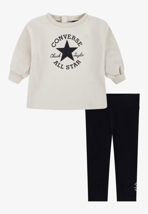 Felpa crema con logo a stella nera e testo, abbinata a leggins neri. La felpa ha polsini e scollatura a costine; i leggins sono elasticizzati.