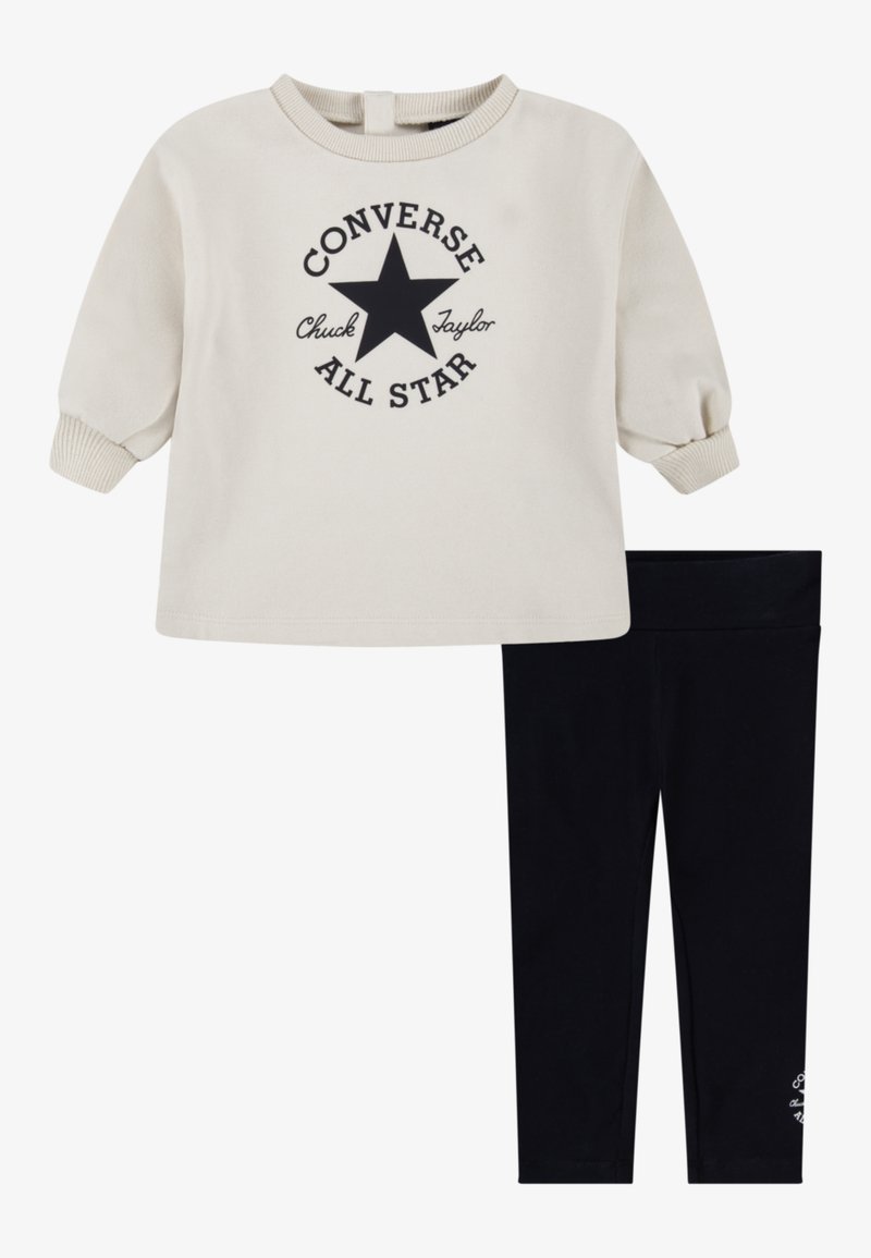 Felpa crema con logo a stella nera e testo, abbinata a leggins neri. La felpa ha polsini e scollatura a costine; i leggins sono elasticizzati.