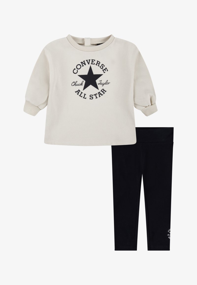 Felpa crema con logo a stella nera e testo, abbinata a leggins neri. La felpa ha polsini e scollatura a costine; i leggins sono elasticizzati.