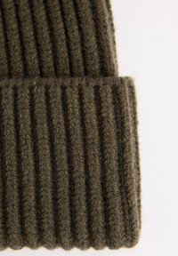 Dark green knitted beanie made from textured wool. Features a ribbed design with vertical lines and a folded hem at the bottom.
