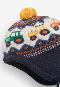 Pletena kapa s tamnoplavom podlogom, koja sadrži šareni uzorak traktora, teksturirani kremasti rub i žutu pom-pom kapi.