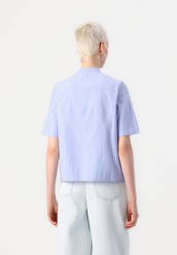 Chemise à manches courtes rayée bleu clair et blanc, dotée d'une coupe droite et d'un design légèrement court.