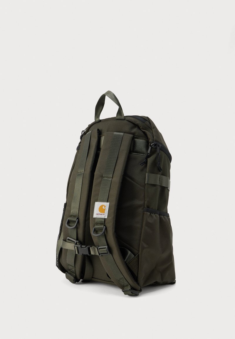 Zaino verde scuro con spallacci imbottiti, tasche laterali in rete e toppa con logo. Realizzato in materiale sintetico resistente.