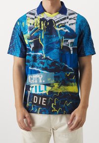 Pánská polokošile s krátkým rukávem v modré barvě s grafickými potisky. Obsahuje žluté akcenty, výrazný text a kombinaci textur. Má límeček s knoflíky.