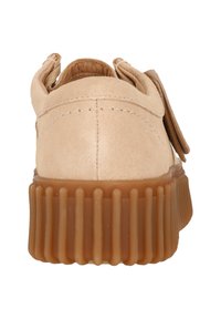 Beige Wildlederschuh mit einer dicken, strukturierten Gummisohle. Mit einer runden Form und genähten Details an der Ferse, sowie doppelten Ösen für die Schnürsenkel.